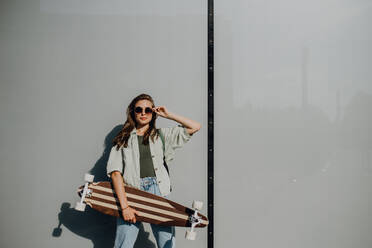 Portrait of young woman outdoor with a skateboard. Youth culture and commuting concept. - HPIF12484