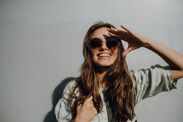 Porträt einer glücklichen jungen Frau im Freien mit Rucksack und Sonnenbrille. - HPIF12488