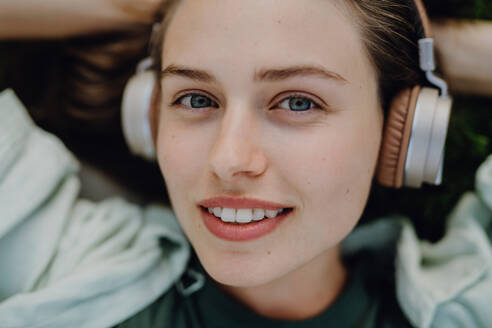 Porträt einer jungen Frau, die über Kopfhörer Musik hört. - HPIF12506