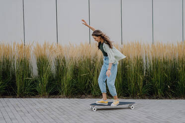 Young woman ridding a skateboard in a city. Youth culture and commuting concept. - HPIF12515