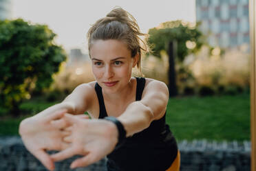 Young woman doing stretching in a city, preparing for run, healthy lifestyle and sport concept. - HPIF12535