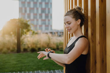 Junge Frau, die in der Stadt eine Smartwatch überprüft und sich auf einen Lauf vorbereitet, Konzept für gesunden Lebensstil und Sport. - HPIF12537