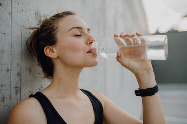 Young woman drinking water during jogging in a city, healthy lifestyle and sport concept. - HPIF12548