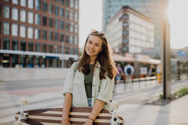 Junge Frau zu Fuß in der Stadt mit einem Skateboard. Jugendkultur und Pendler Konzept. - HPIF12638