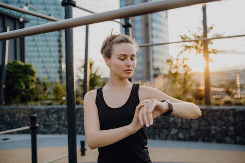 Junge Frau, die in der Stadt eine Smartwatch überprüft und sich auf einen Lauf vorbereitet, Konzept für gesunden Lebensstil und Sport. - HPIF12647