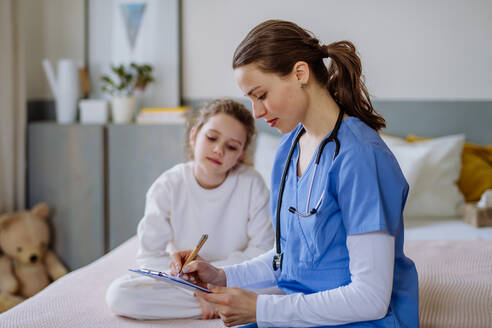 Junge Ärztin, die sich um ein kleines Mädchen in einem Krankenhauszimmer kümmert. - HPIF12652