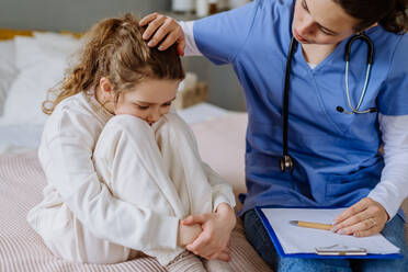 Junge Ärztin, die sich um ein kleines Mädchen in einem Krankenhauszimmer kümmert. - HPIF12656