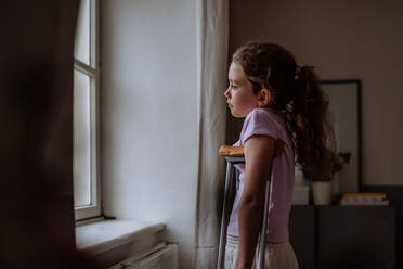 Little girl with broken leg looking trough the window. - HPIF12684