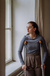 Teenage girl with broken leg looking trough the window. - HPIF12698