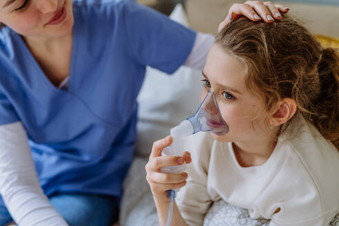 Kleines Mädchen mit Inhalator im Krankenhauszimmer, eine Krankenschwester kümmert sich um sie. - HPIF12712