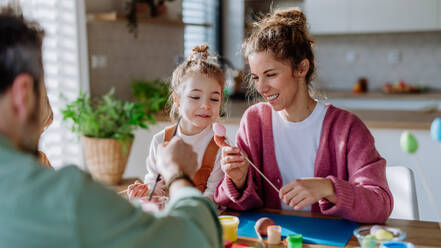 Happy family with little child decorating easter eggs in their home. - HPIF12733