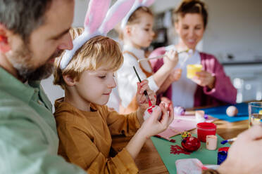 Glückliche Familie mit kleinen Kindern beim Verzieren von Ostereiern in ihrem Haus. - HPIF12735