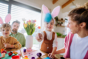Glückliche Familie mit kleinen Kindern beim Verzieren von Ostereiern in ihrem Haus. - HPIF12739