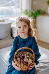 Porträt eines kleinen Mädchens, das einen Korb mit Ostereiern hält. - HPIF12762
