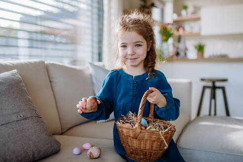 Porträt eines kleinen Mädchens, das einen Korb mit Ostereiern hält. - HPIF12767