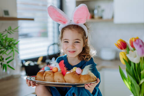 Kleines Mädchen, das ein Ostergebäck hält, um Ostern und den Frühling zu feiern. - HPIF12798