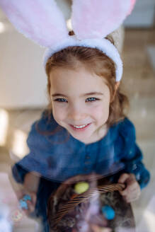 Porträt eines kleinen Mädchens, das einen Korb mit Ostereiern hält. - HPIF12802
