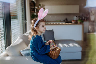 Porträt eines kleinen Mädchens, das einen Korb mit Ostereiern hält. - HPIF12803