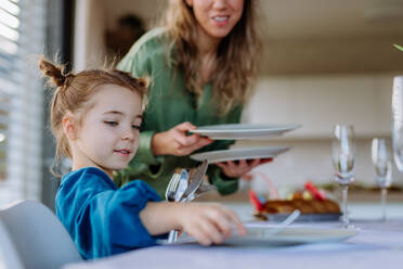 Nahaufnahme einer Mutter mit ihrer Tochter, die den Tisch deckt, um Ostern zu feiern. - HPIF12805
