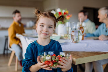 Kleines Mädchen hält Schüssel mit Salat, Vorbereitungen für ein Familienessen. - HPIF12815