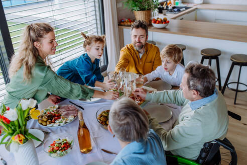 Fröhliche Familie stößt vor einem Osteressen an. - HPIF12829