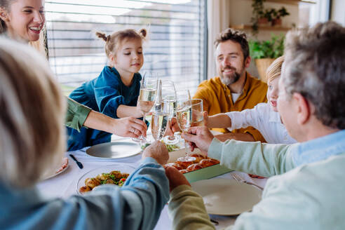 Fröhliche Familie stößt vor einem Osteressen an. - HPIF12830