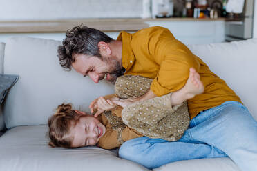 Ein Vater kitzelt seine kleine Tochter und hat Spaß mit ihr. - HPIF12847