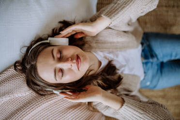 Draufsicht auf eine junge Frau, die über einen Kopfhörer Musik hört. - HPIF12850