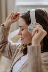 Young woman listening music trough headphones in the apartment. - HPIF12852