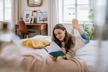 Young woman enjoying leisure time in her apartment, reading a book. - HPIF12864