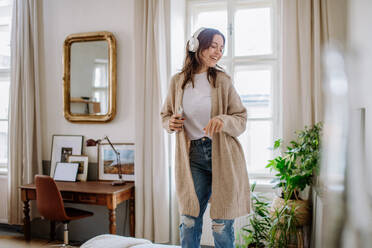 Young woman listening music trough headphones in the apartment. - HPIF12865