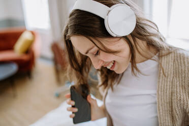 Young woman listening music trough headphones in the apartment. - HPIF12869