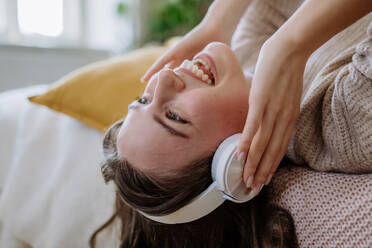 Junge Frau hört Musik über Kopfhörer in der Wohnung. - HPIF12871