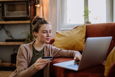 Junge Frau beim Online-Shopping in der Wohnung. - HPIF12881