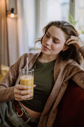 Young woman sitting on sofa with a drink. - HPIF12891