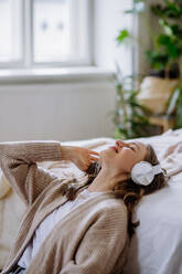 Young woman listening music trough headphones in the apartment. - HPIF12897