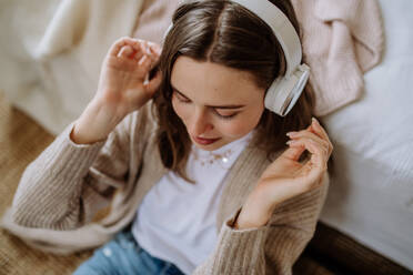 Junge Frau hört Musik über Kopfhörer in der Wohnung. - HPIF12899