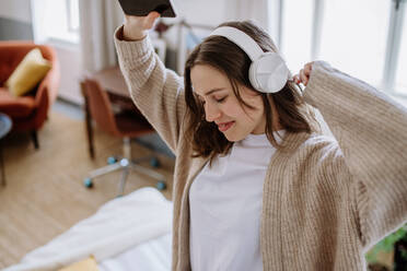 Young woman listening music trough headphones in the apartment. - HPIF12907