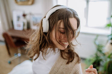 Junge Frau hört Musik über Kopfhörer in der Wohnung. - HPIF12908