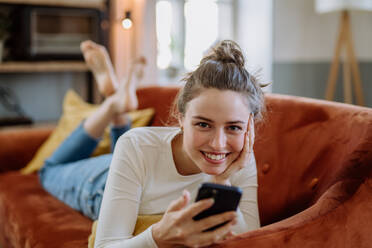 Young woman scrolling her smartphone in an apartment. - HPIF12914