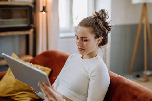 Junge Frau mit digitalem Tablet, die sich in der Wohnung ausruht. - HPIF12915