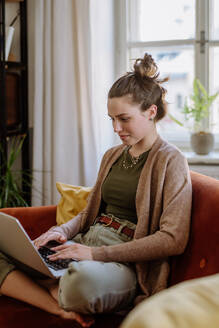 Junge Frau mit digitalem Tablet, die sich in der Wohnung ausruht. - HPIF12921