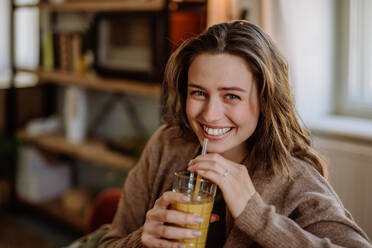 Young woman sitting on sofa with a drink. - HPIF12935