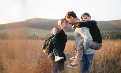 A beautiful young family with small children on a walk in autumn nature, having fun. - HPIF12977