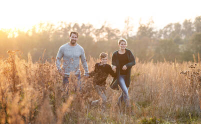 Beautiful young family with small son on a walk in autumn nature, having fun. - HPIF12979