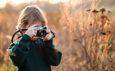 Small girl in autumn nature, taking photographs with camera. Copy space. - HPIF12980