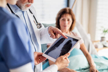 Senior male doctor with nurse examining a woman patient in hospital, checking X-ray. - HPIF13019