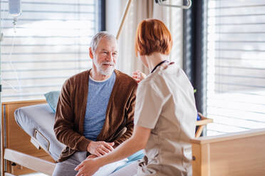 A friendly female doctor talking to senior patient in bed in hospital. - HPIF13033