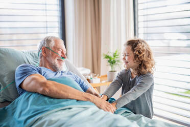 Ein fröhliches kleines Mädchen, das seinen kranken Großvater im Krankenhauszimmer besucht. - HPIF13041