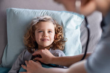 Eine nicht erkennbare Ärztin mit Stethoskop untersucht ein kleines Mädchen im Bett im Krankenhaus. - HPIF13046